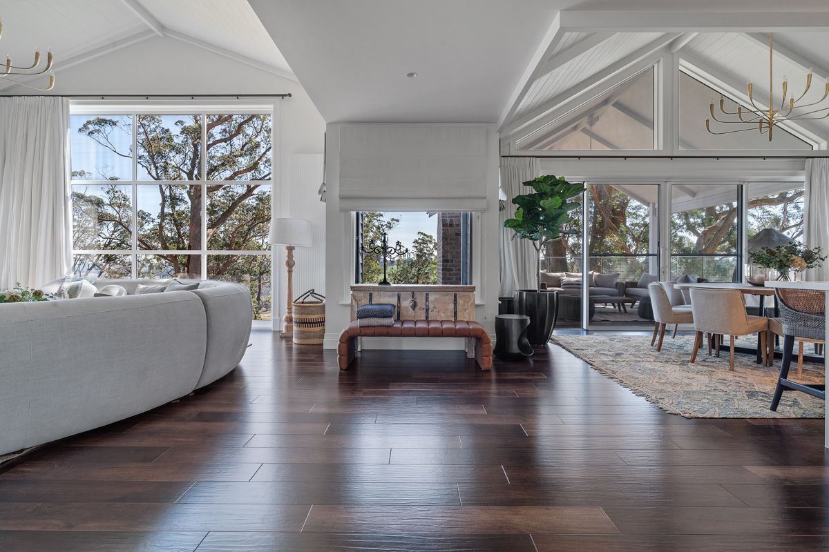 Bright open living room with dark wood floors, large windows, white sofa, and dining area