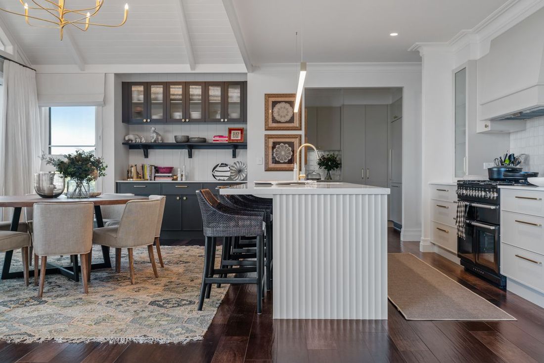 Bright modern kitchen with island, white cabinets, dark wood floors, and adjacent dining area