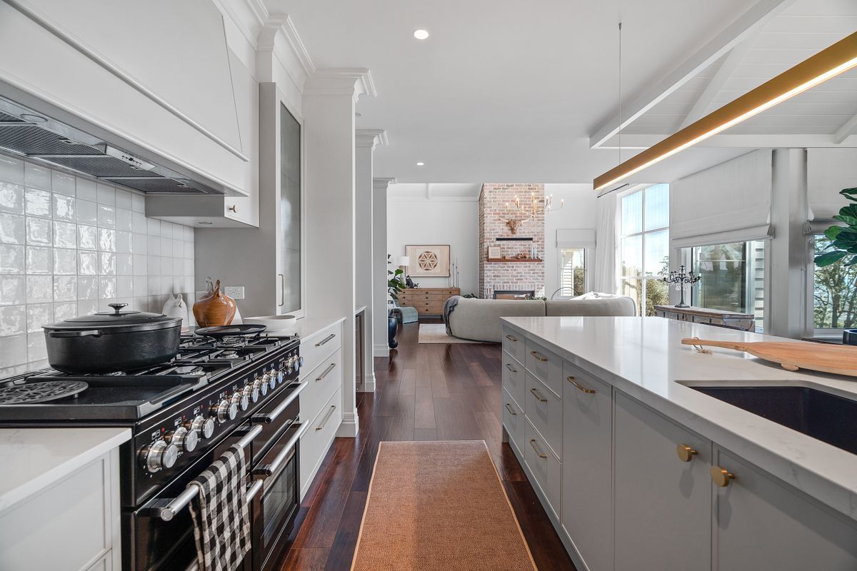 Bright modern kitchen with white cabinets, black stove, and island overlooking a dining area