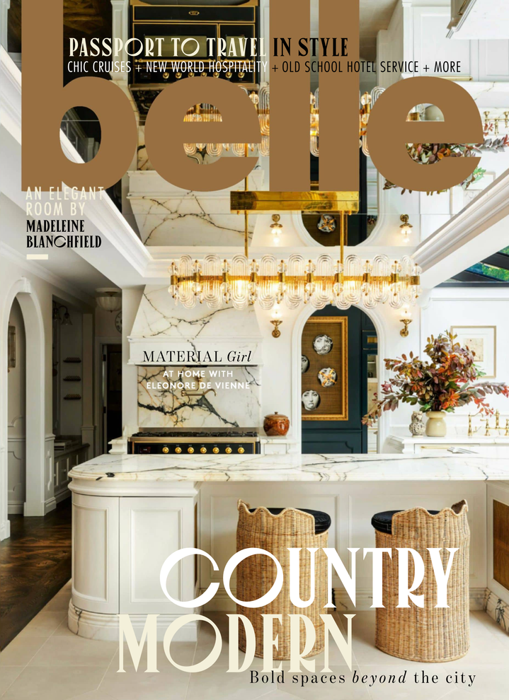 Stylish white country-modern kitchen with brass accents and chandelier, featured in a magazine cover