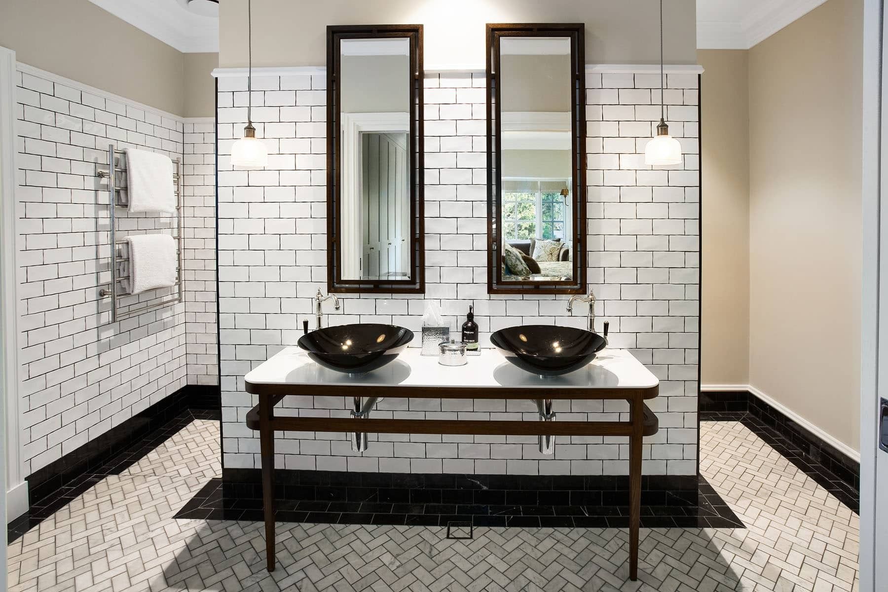 Elegant restroom with white subway tile, black accents, and two vessel sinks under tall mirrors
