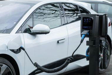 White electric car charging at a public station outdoors