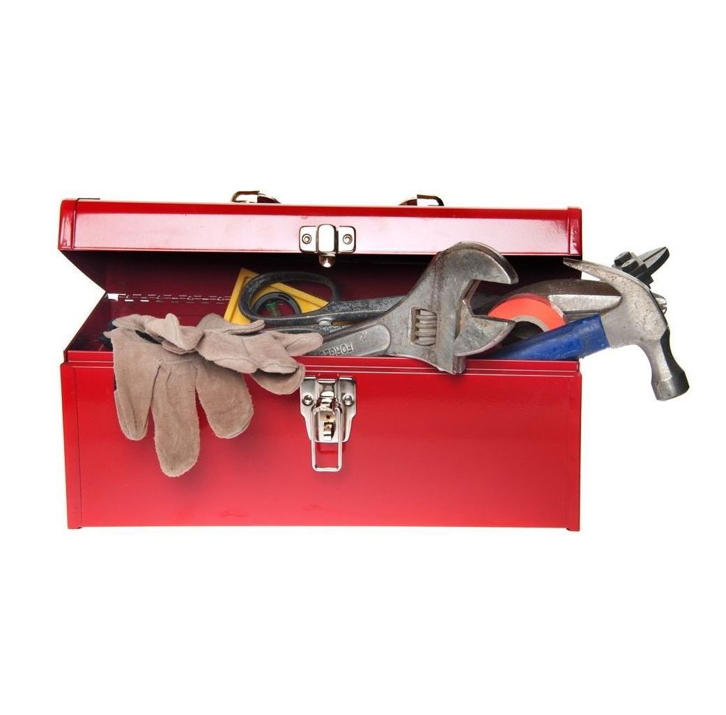 A man in overalls is holding a toolbox in a kitchen.