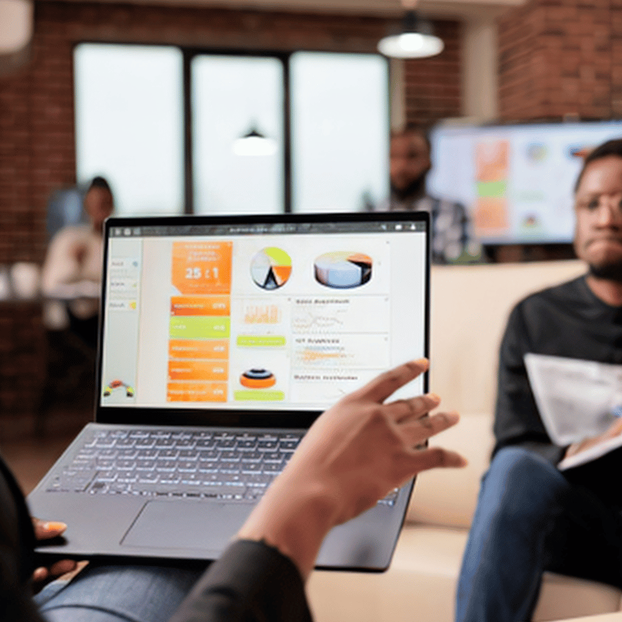 Laptop displaying charts during office meeting, with a hand pointing at the screen