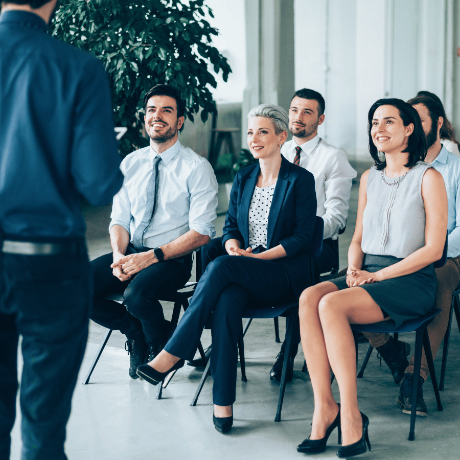 People seated in a bright office listening to a speaker during a presentation