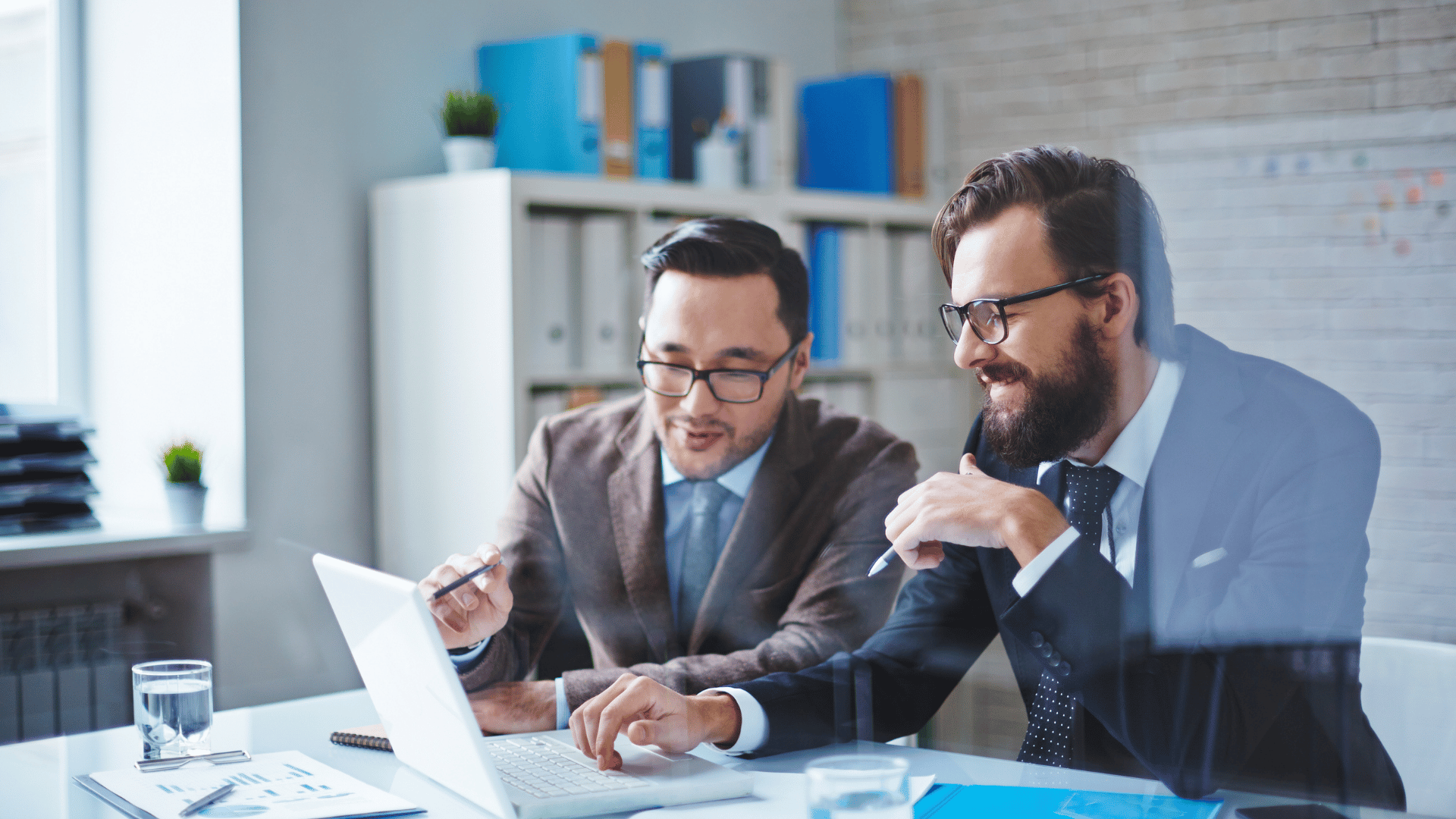 Two people in a meeting with charts, speech bubbles, and a document, discussing ideas in a workspace.