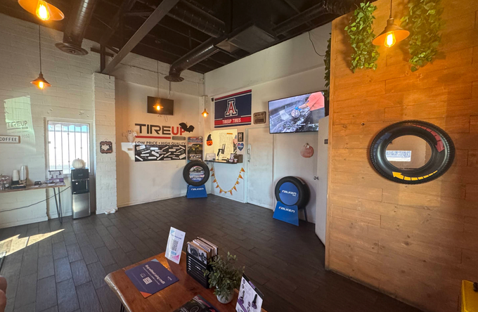 Modern lobby with tire displays, wood accent wall, TV, and orange pendant lights | TireUp Tires| Wheel Alignment, Brakes & Service
