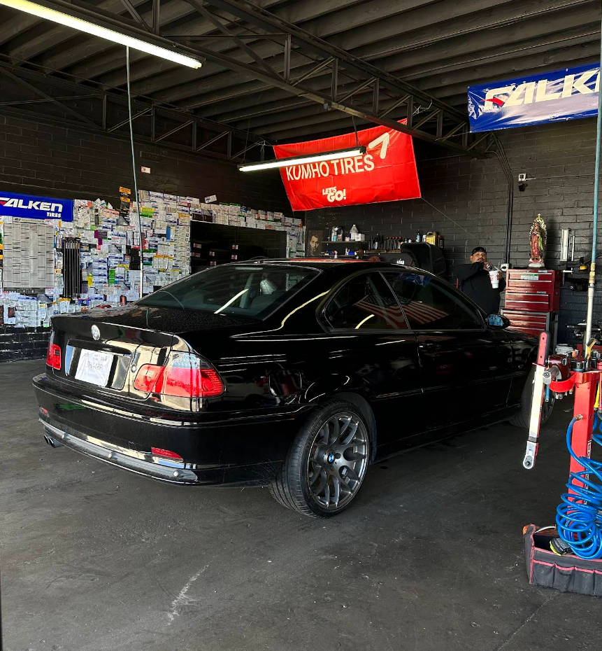Black sedan in an auto repair shop with a red Valvoline banner overhead | TireUp Tires| Wheel Alignment, Brakes & Service