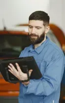 Mechanic inspecting car brake rotor on a vehicle lift.