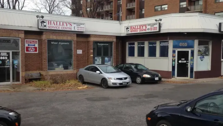 Exterior of a brick building with two businesses; cars parked in front.