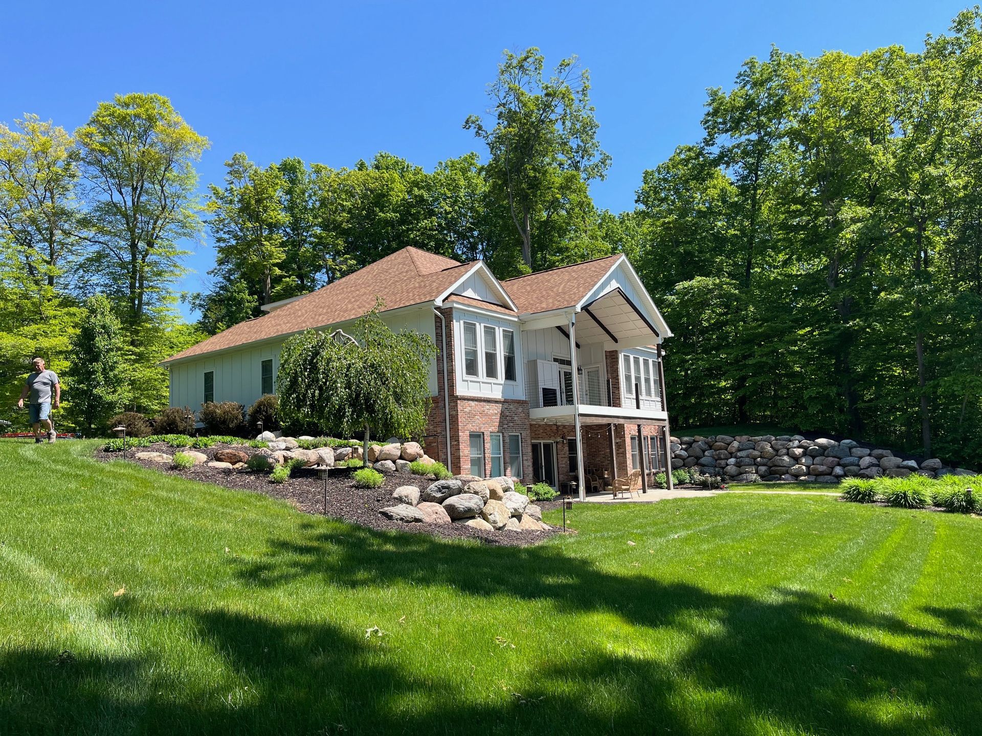 A large house is sitting on top of a lush green hill surrounded by trees.