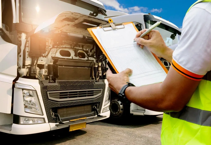 Mechanic inspecting a truck engine with a clipboard in bright daylight