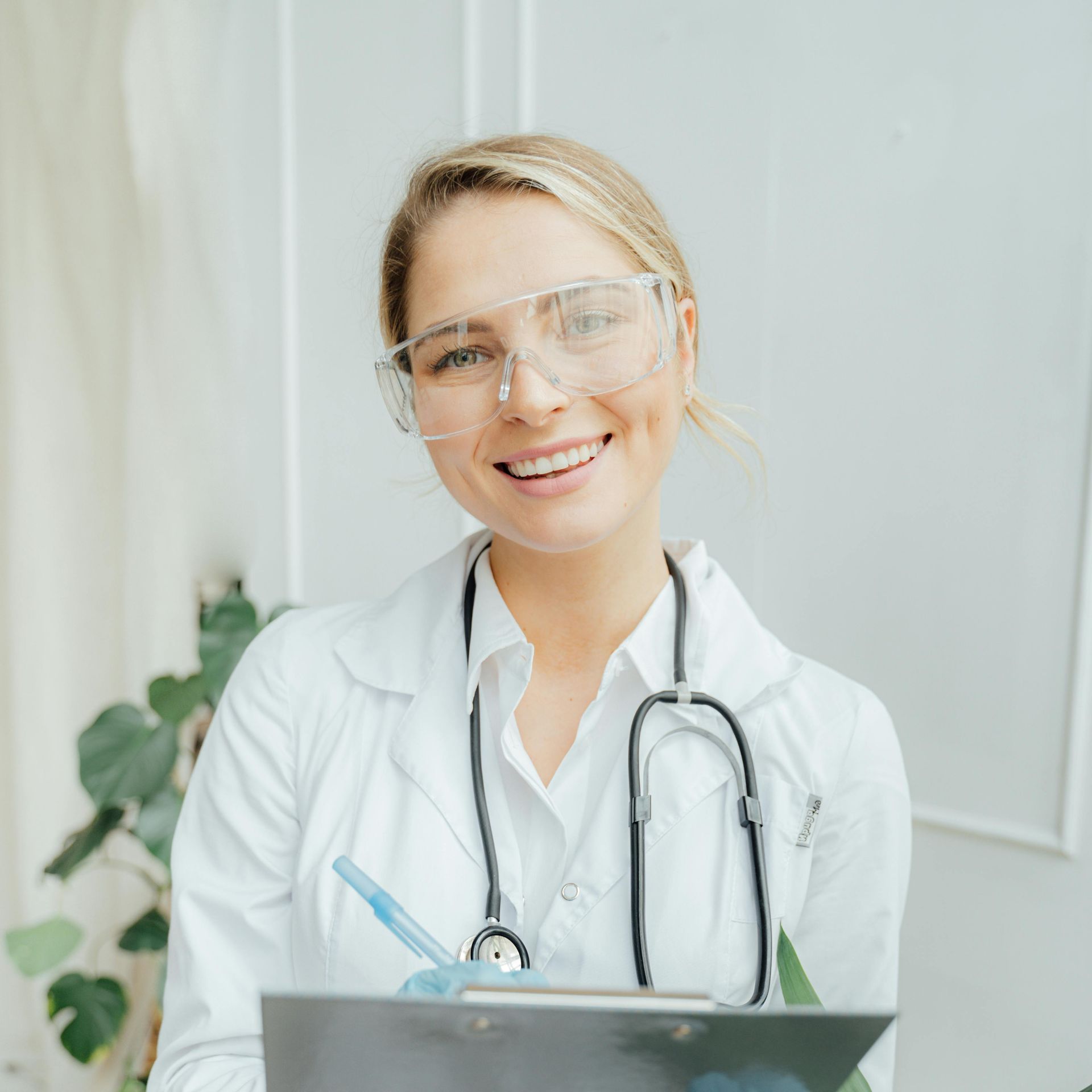A female doctor is holding a clipboard and smiling.