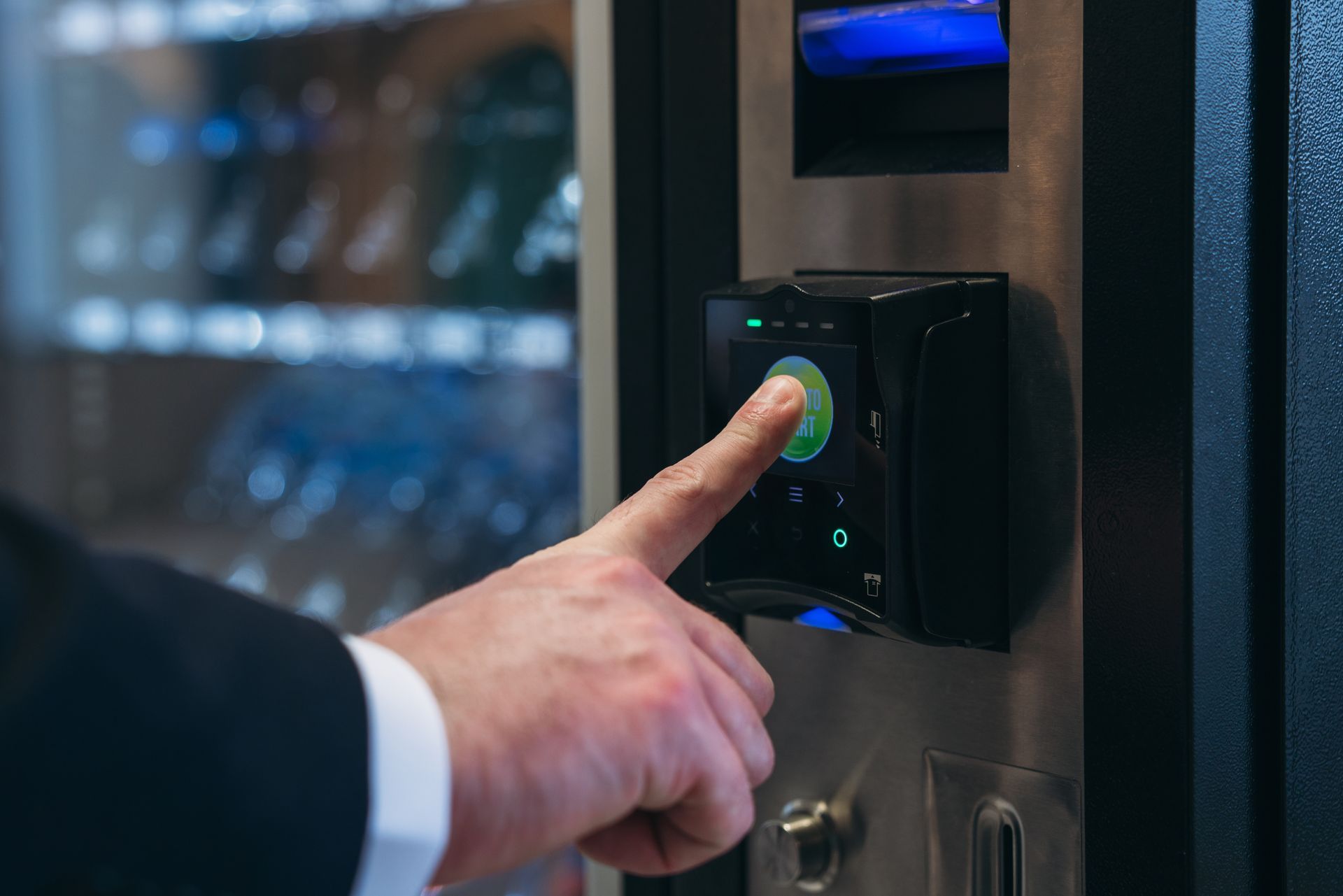Hand pressing a button on an office vending machine touchscreen.
