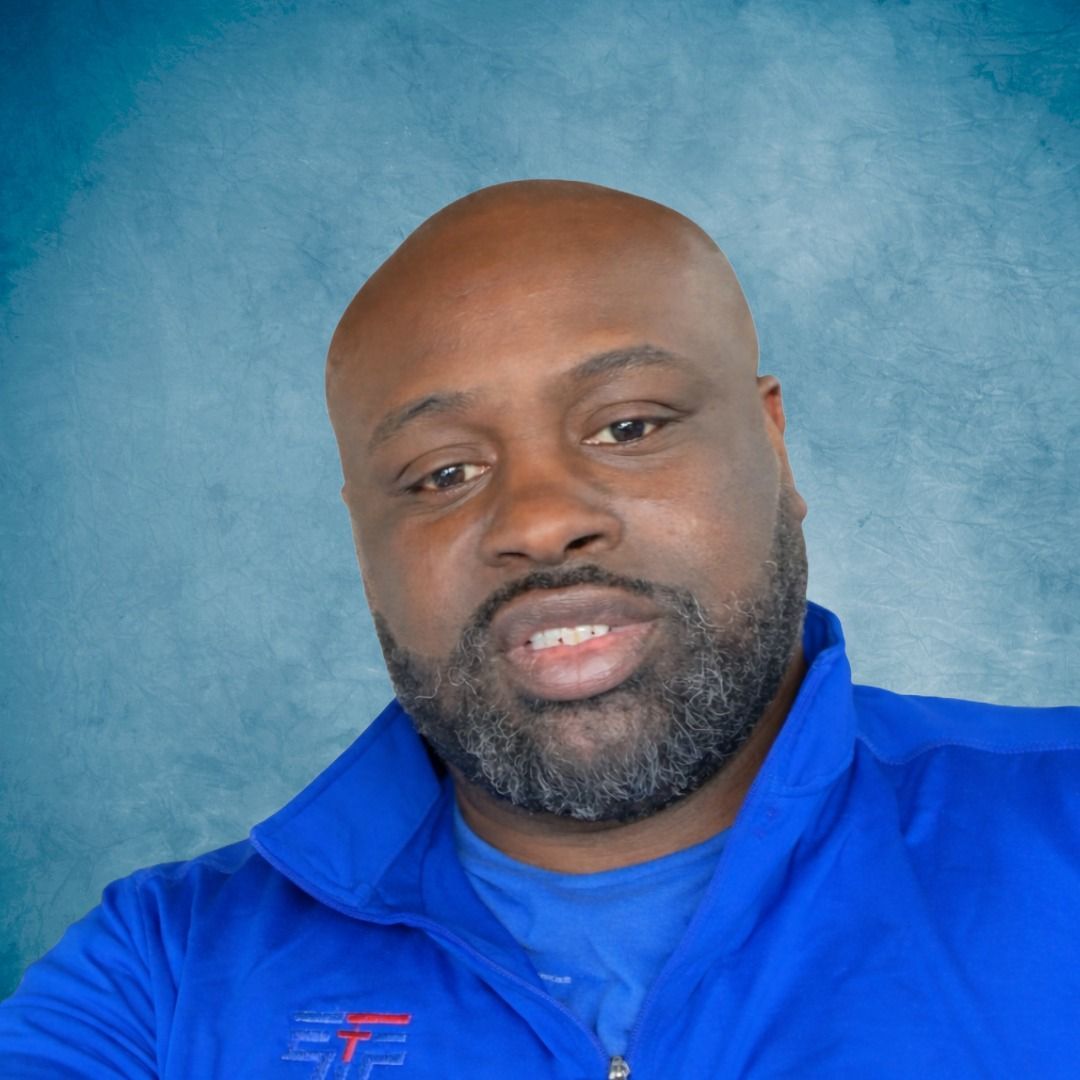 A man is standing in front of a blue background.