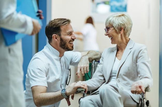 A doctor is talking to an elderly woman in a wheelchair.