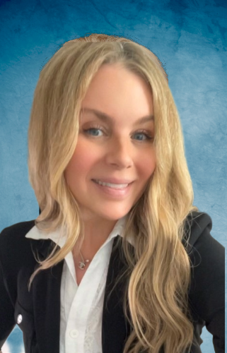 Blonde woman with wavy hair, smiling, wearing a black blazer and white top, against a blue backdrop.
