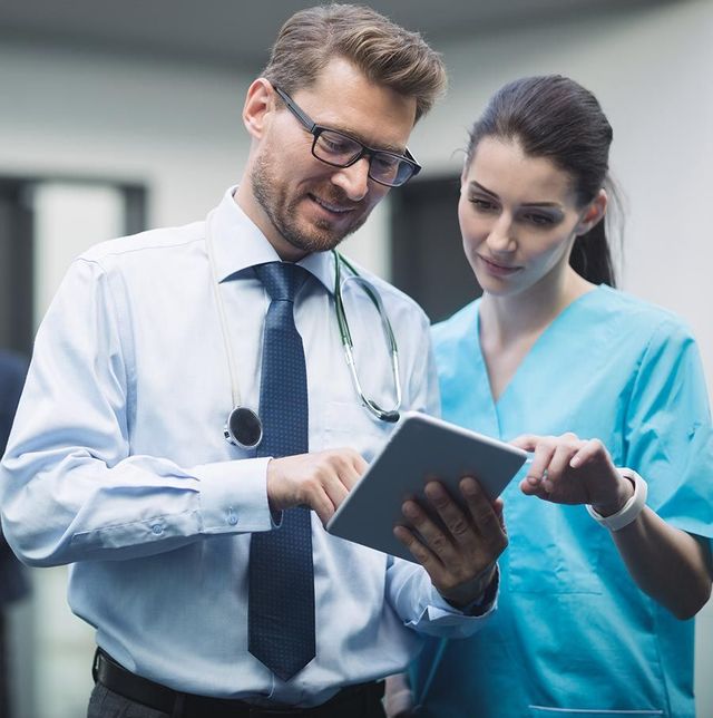 A doctor and nurse are looking at a tablet together.