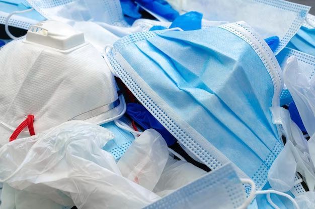 A pile of surgical masks and gloves on a table.