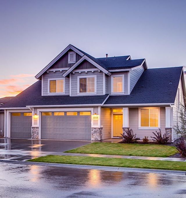 A large house with two garage doors and a sunset in the background