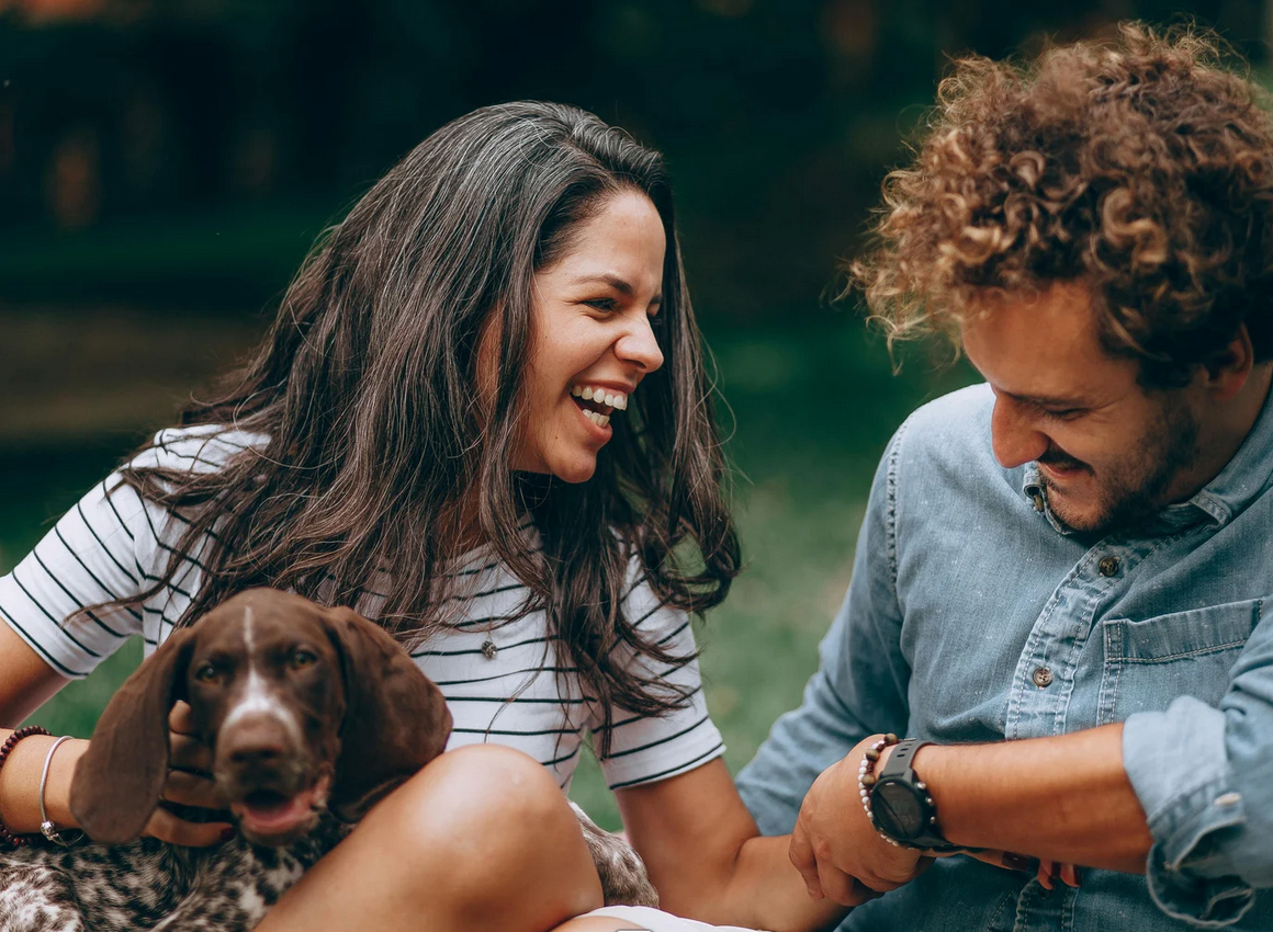 Happy couple smiling with their dog outdoors
