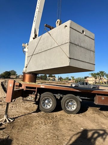 Crane lifting a large concrete block at a construction site.