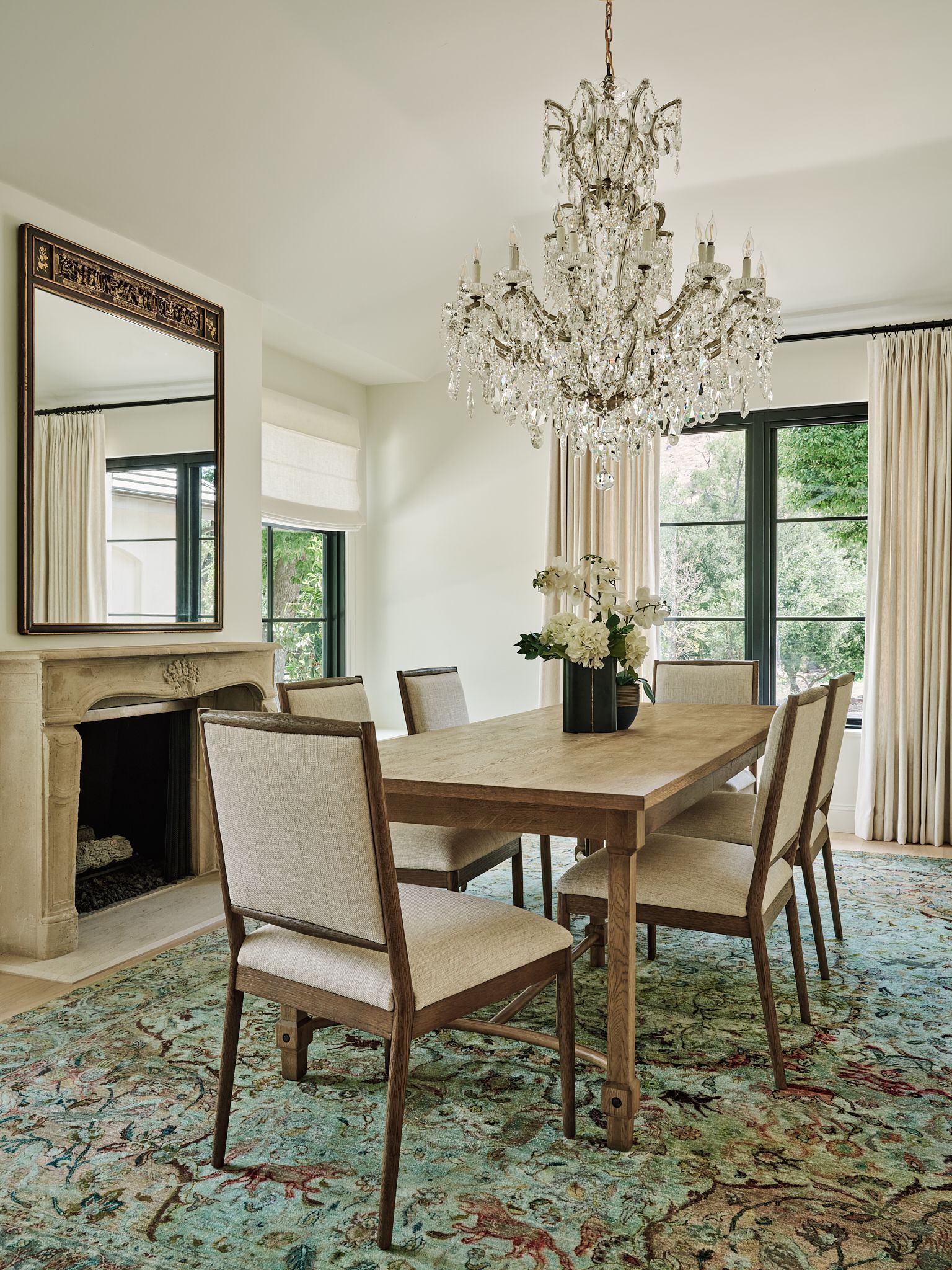 Open-concept kitchen with island, stainless steel sink, and large windows overlooking a green yard and blue sky.