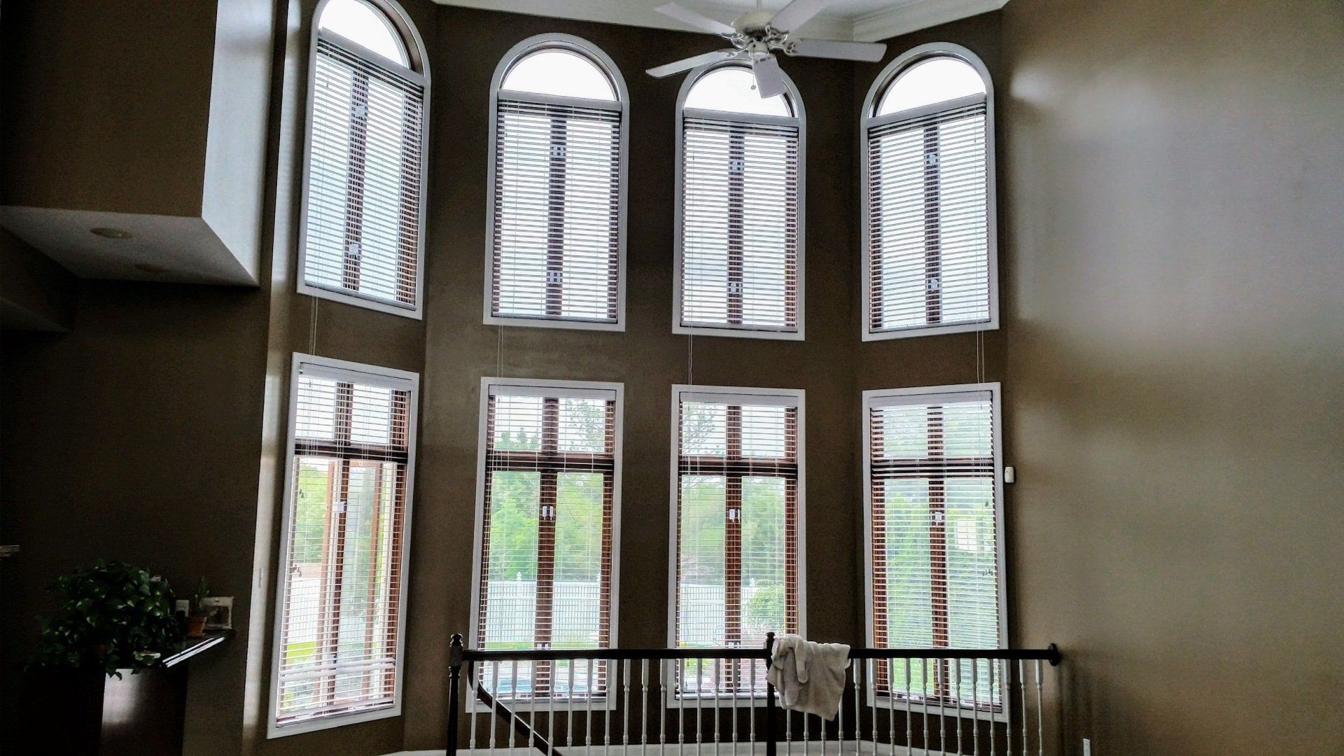 Tall arched windows overlooking a staircase in a bright interior lobby