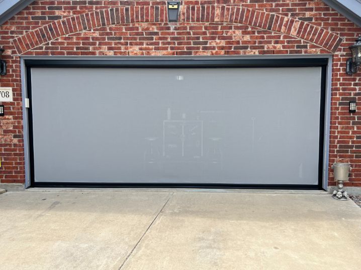 Gray garage door set in a red brick wall above a concrete driveway