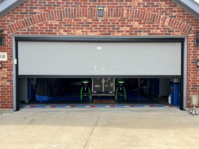 Brick house with garage door partly open, showing a small go-kart inside.
