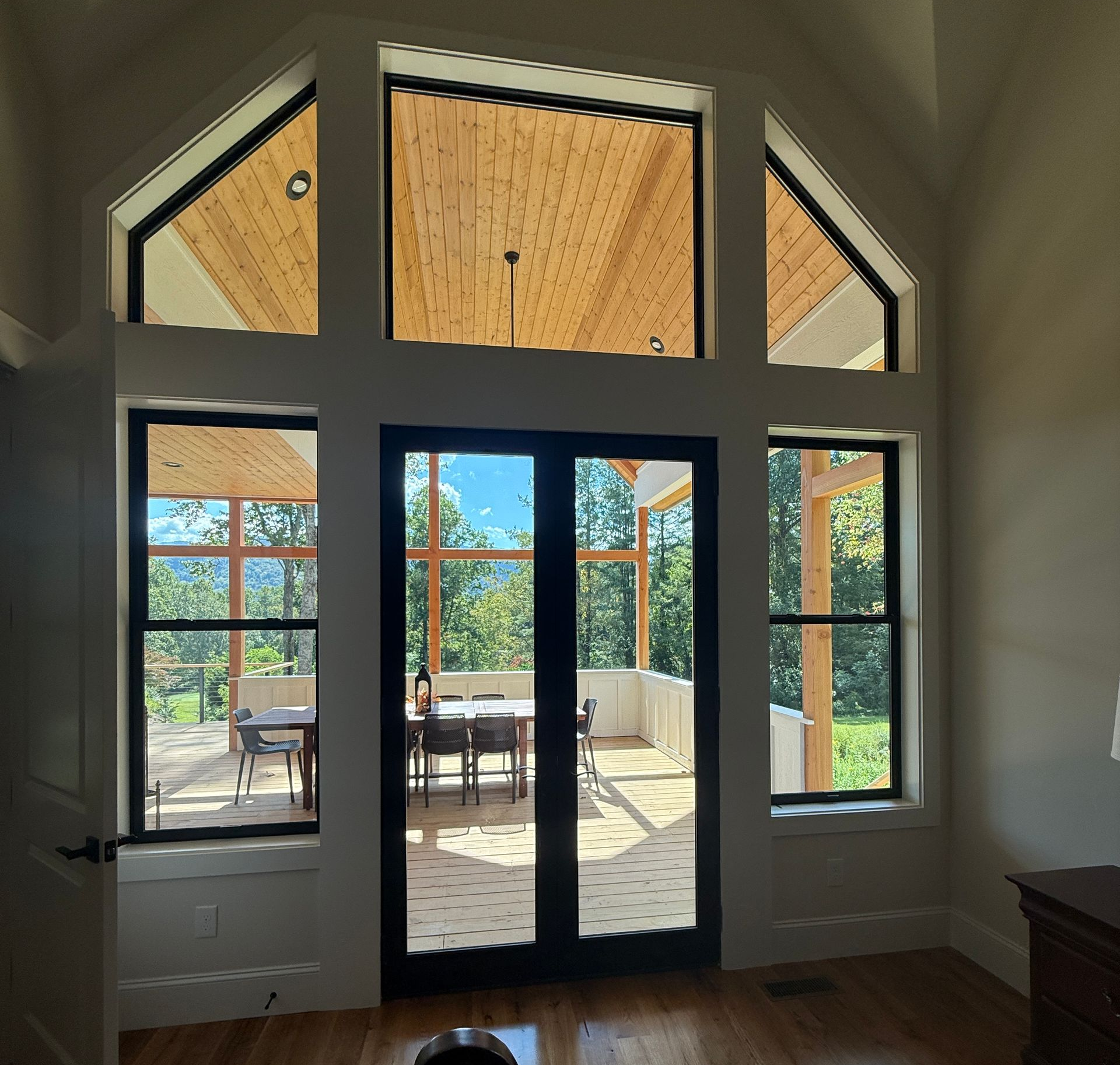 Bright living room with French doors and transom windows opening to a patio and outdoor seating