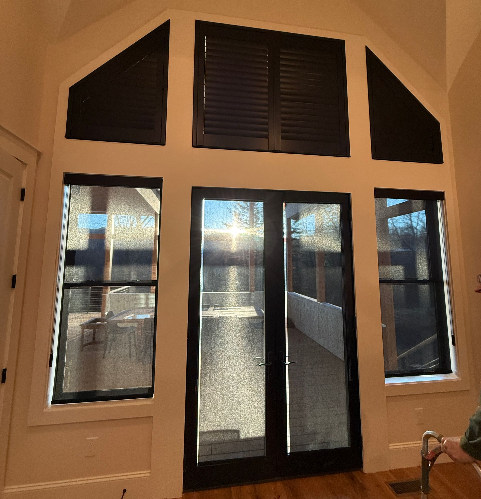 Tall arched glass doors and windows in a bright interior, with sunlight streaming through.