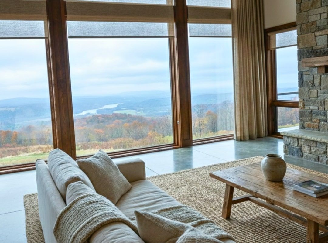 Cozy living room with sofa and woven table overlooking a scenic mountain and lake view through large windows