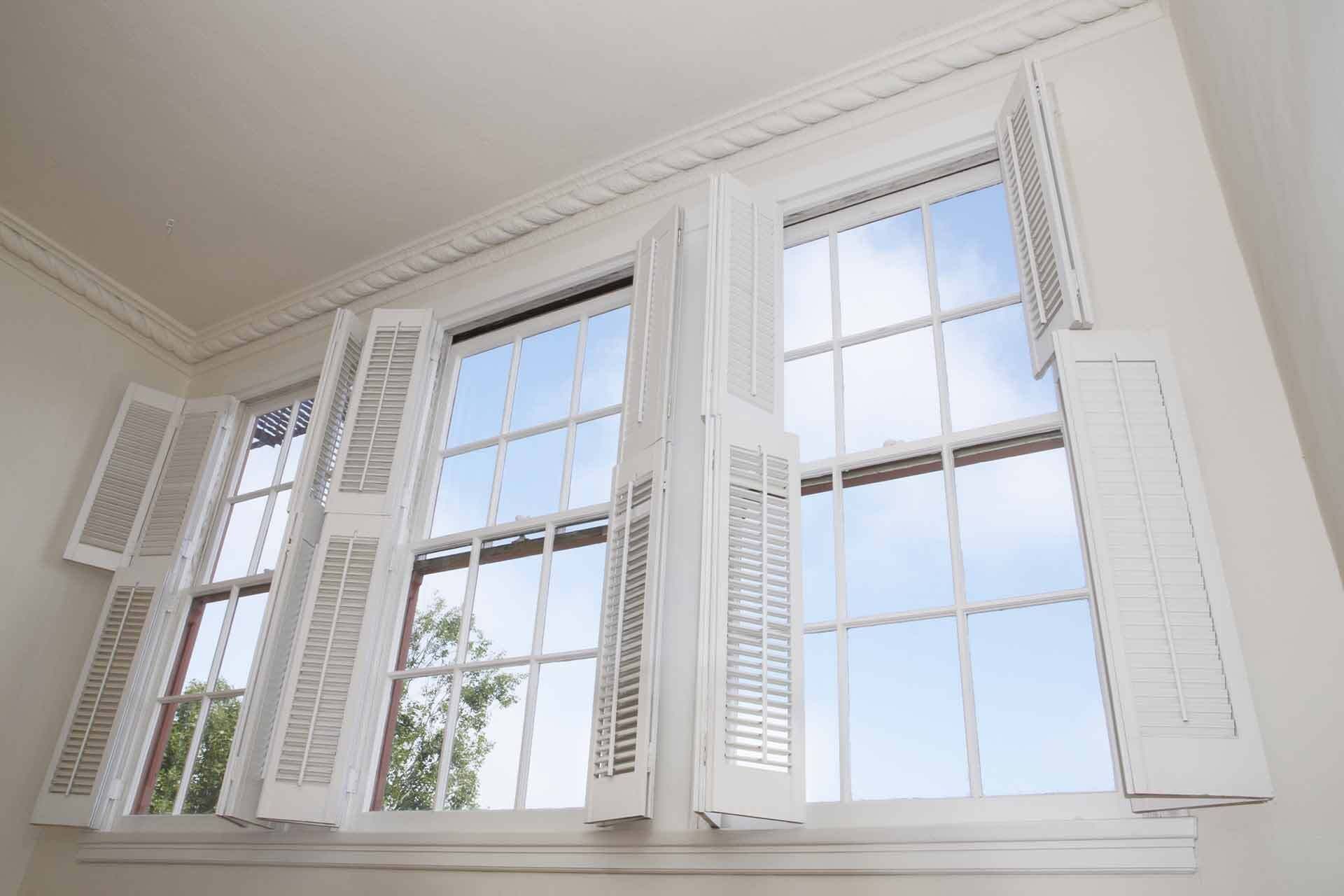 Bright white bay windows with open shutters in a sunlit room