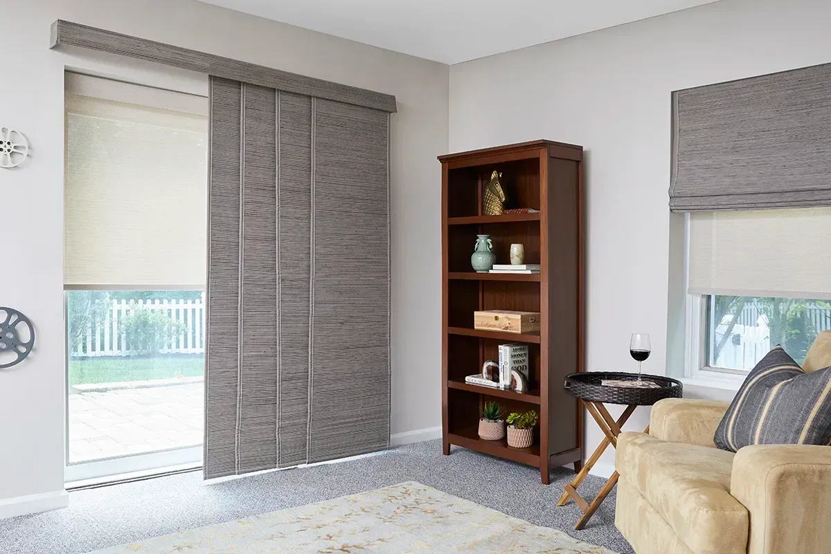 Bright living room with sliding door blinds, bookshelf, and a beige sofa by the window.