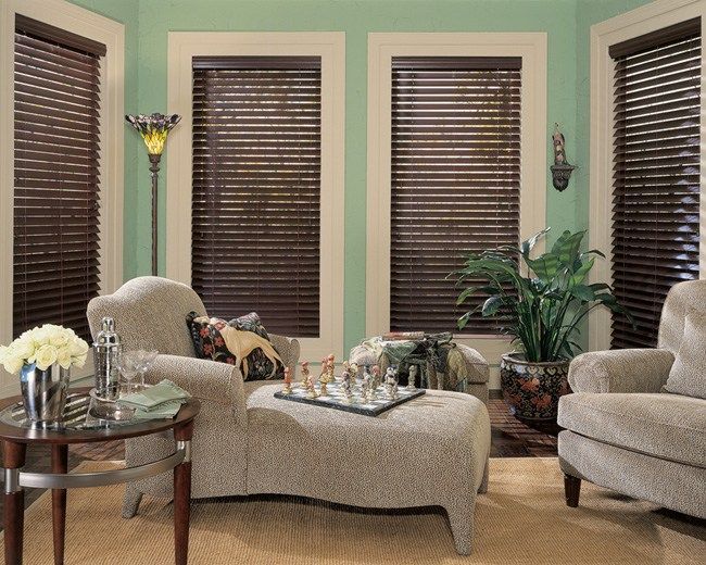 Cozy living room with beige chairs, chaise lounge, dark blinds, and potted plants