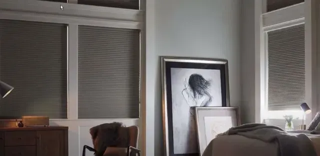 Dim room with windows, a desk, and framed artwork leaning against a wall.