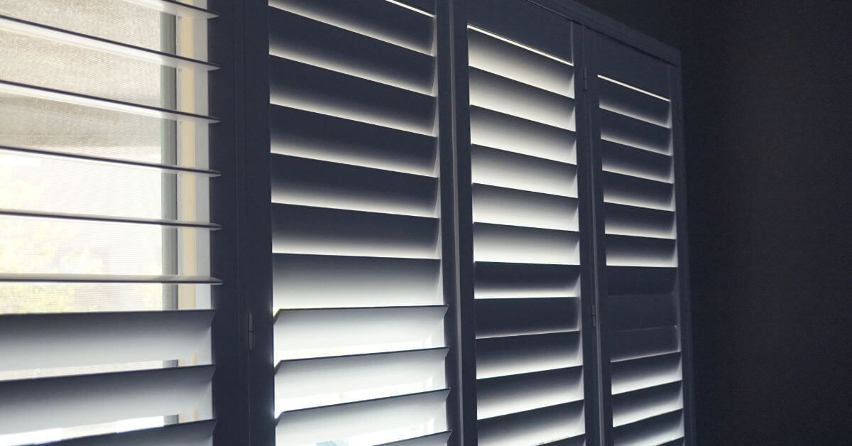 Sunlight filtering through white window blinds in a dim room