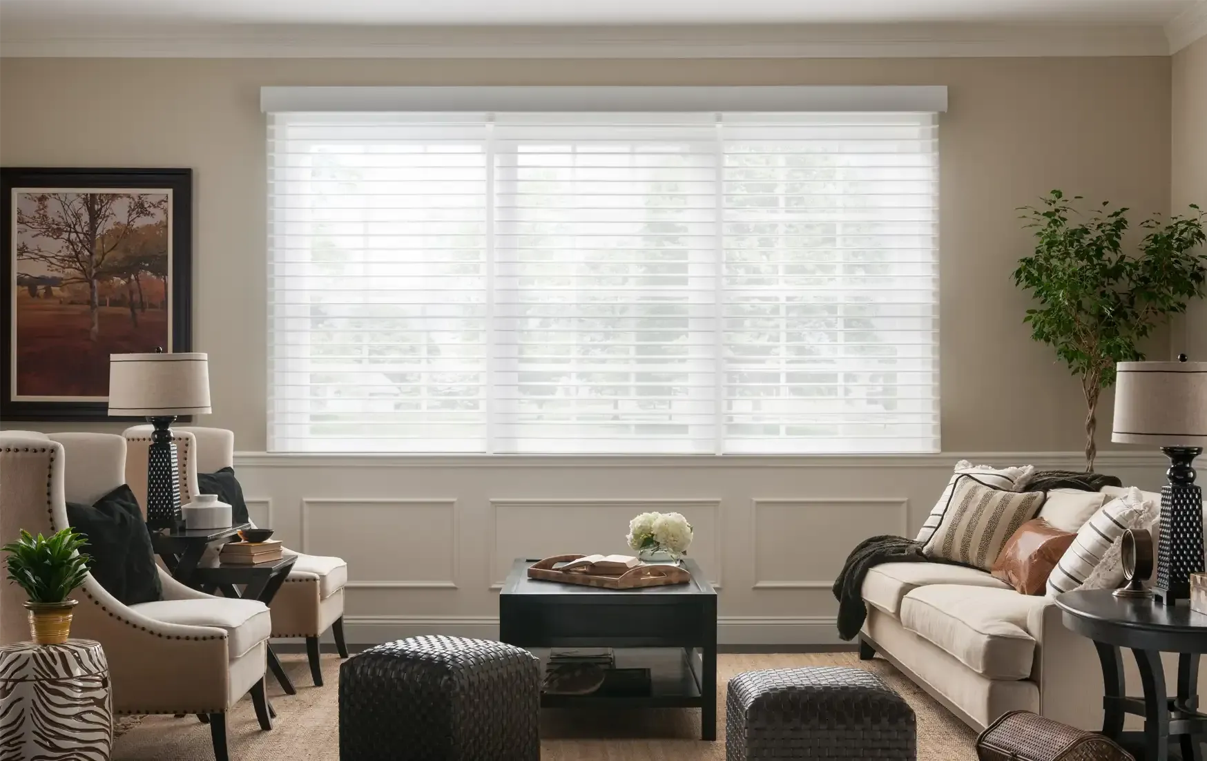 Bright living room with beige sofas, a coffee table, and a large window with white blinds
