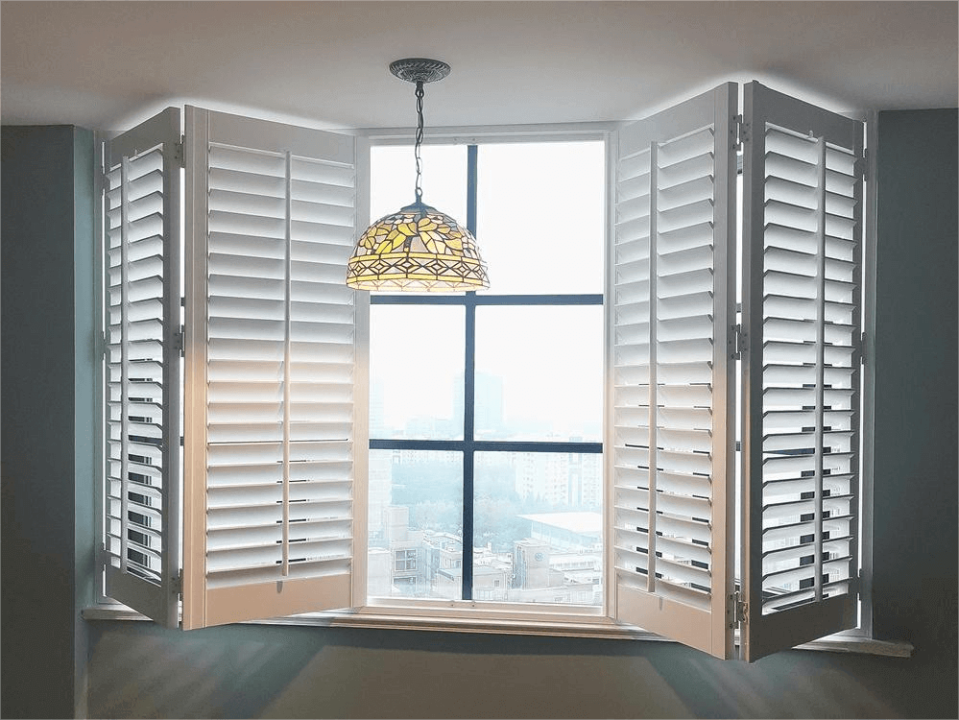 Bay window with white plantation shutters and a hanging stained-glass pendant light