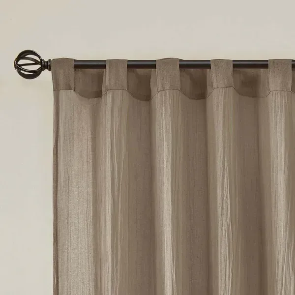 Beige curtain panel hanging from a dark rod against a white wall