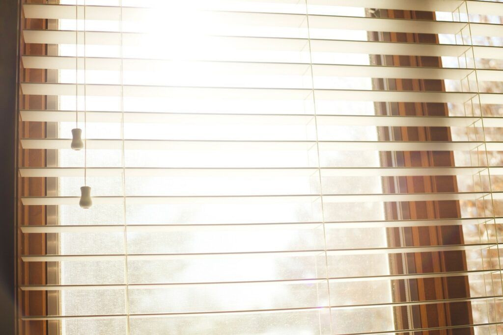 Sunlit window with closed blinds and a bright glow shining through from outside