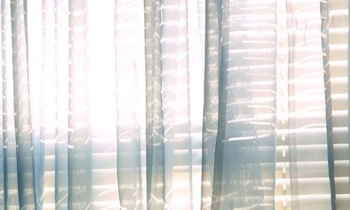 Sheer curtains with soft sunlight streaming through a window