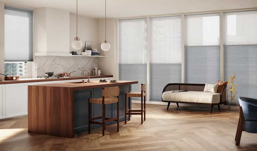 Modern kitchen and living area with wood island, pendant lights, and a sofa by large windows