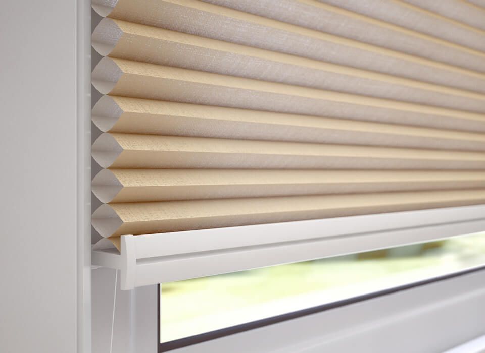 Closed beige pleated window blind with bright light filtering through below
