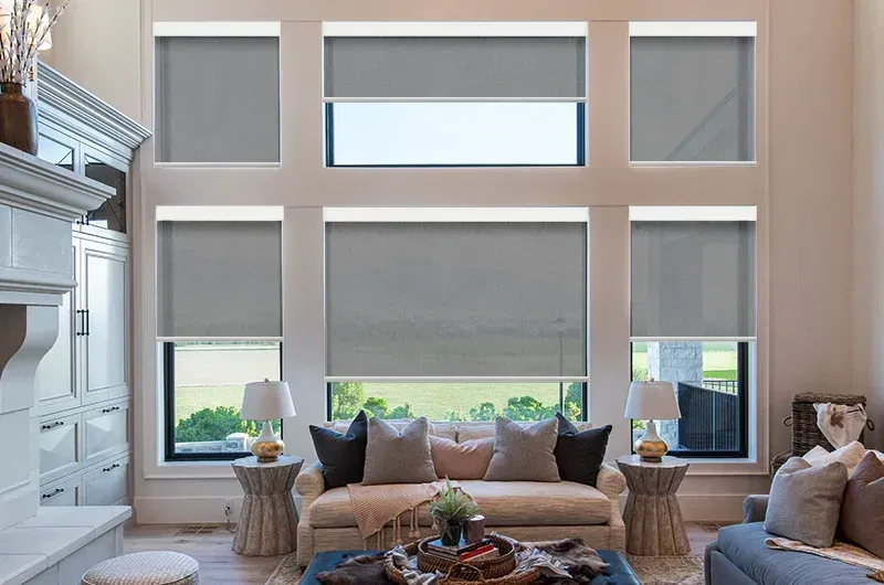Bright living room with large windows, beige sofa, and neutral decor around a coffee table.