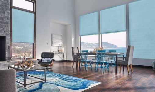 Modern living-dining room with blue decor, large windows, and a city view
