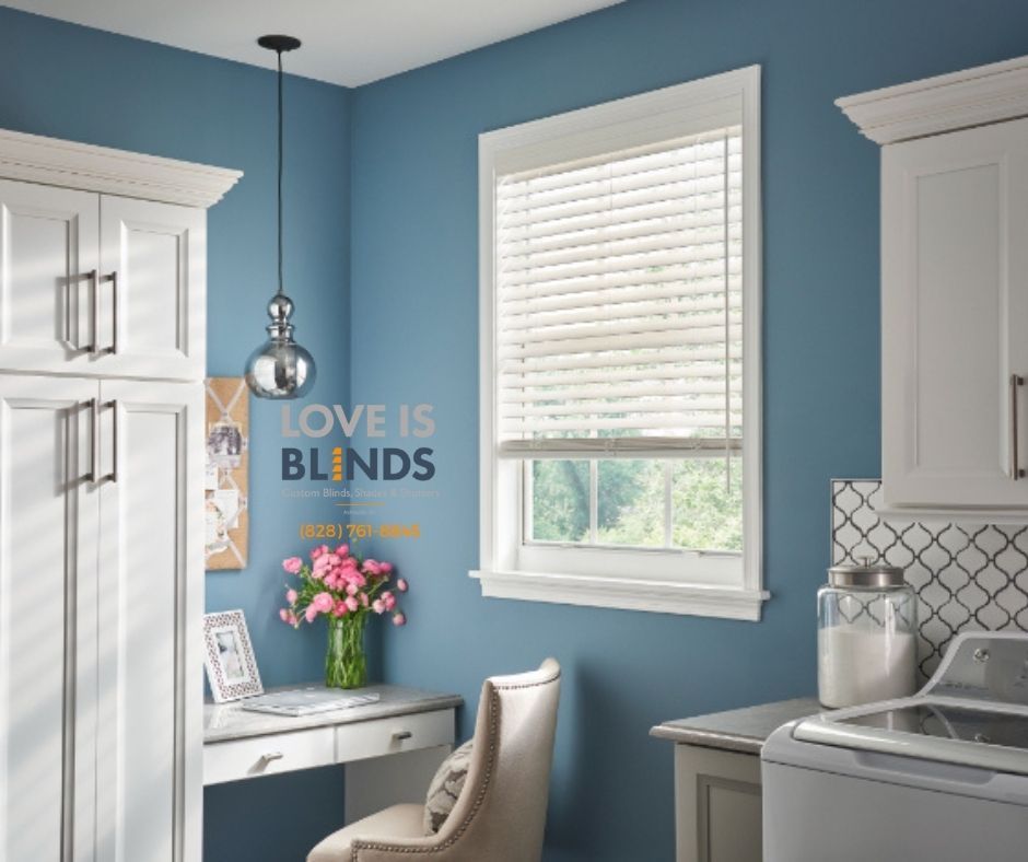 Bright blue laundry room with white cabinets, window, desk, flowers, and wall text “LOVE IS BLINDS.”