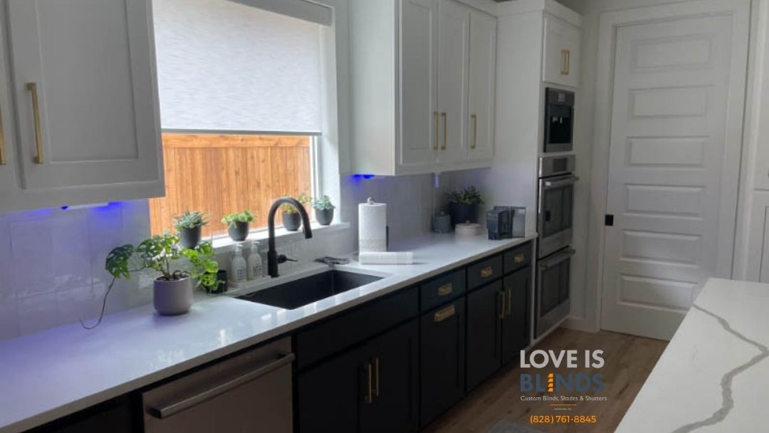 Modern kitchen with white and dark cabinets, marble counters, sink by window, and blue under-cabinet lighting