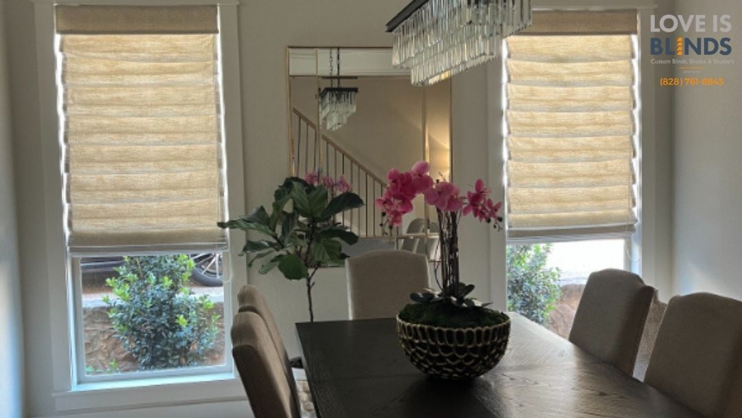 Dining room with dark table, beige chairs, potted orchids, and large windows with woven blinds.